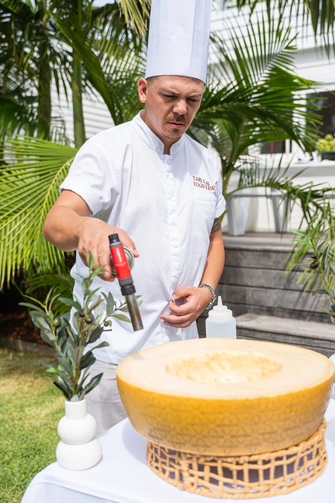Chef Gabriele Franco torching a cheese wheel at a live event